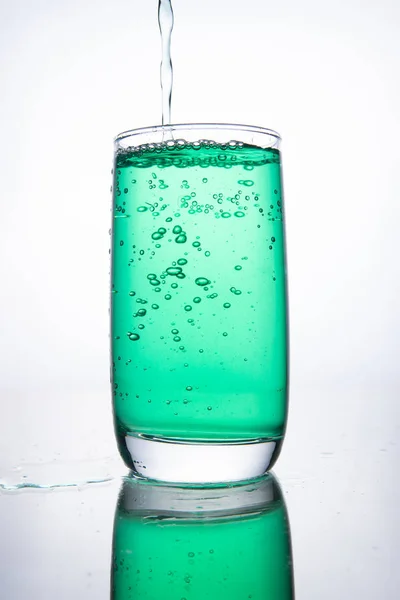Groene cocktail wordt in een glas gegoten op een witte achtergrond met — Stockfoto