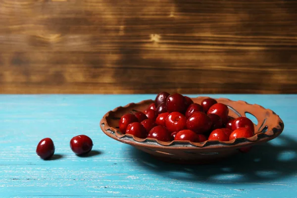 Red sweet cherry in a clay plate on a turquoise wooden table — Stock Photo, Image