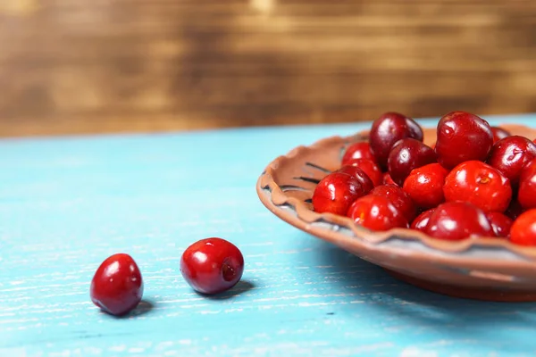 Ciliegia dolce rossa in un piatto di argilla su un tavolo di legno turchese — Foto Stock