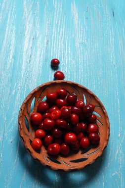 Turkuaz ahşap masada bir kil plaka kırmızı tatlı kiraz
