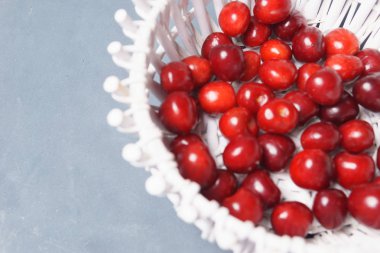 Gri bir arka planda beyaz bir sepet içinde kırmızı tatlı kiraz