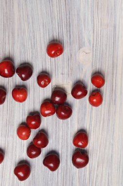 Beyaz ahşap masaya dağılmış kırmızı tatlı kiraz