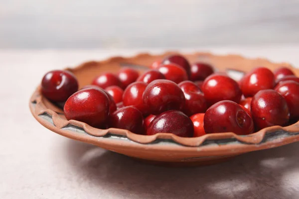 Dolce ciliegia rossa in un piatto di argilla su un tavolo alla panna — Foto Stock