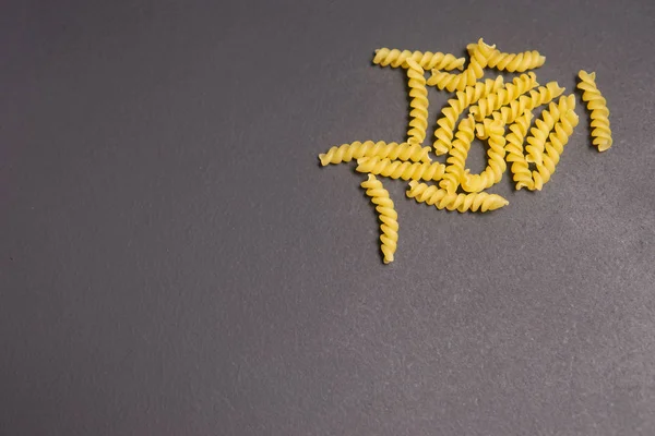 Rohe Pasta in Form einer Spirale auf grauem Hintergrund — Stockfoto