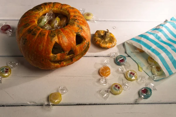 Beyaz bir masada Cadılar Bayramı balkabağı ve şekerler