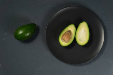 Taze, çiğ avokado siyah bir tabakta dilimlenmiş.
