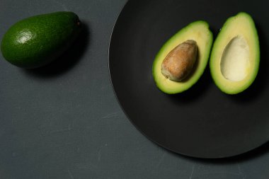 Taze, çiğ avokado siyah bir tabakta dilimlenmiş.