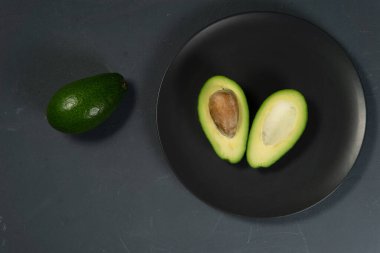 Taze, çiğ avokado siyah bir tabakta dilimlenmiş.