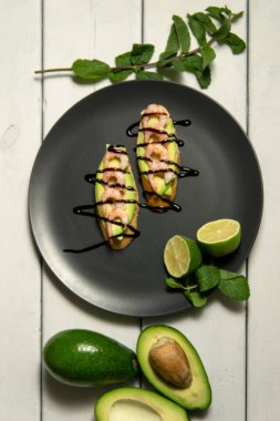 Beyaz ahşap arka planda karides, avokado ve limonlu bruschetta.