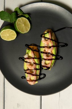 Beyaz ahşap arka planda karides, avokado ve limonlu bruschetta.