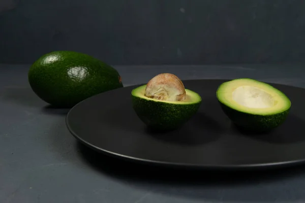Fresh, raw avocado sliced on a black plate — Stock Photo, Image