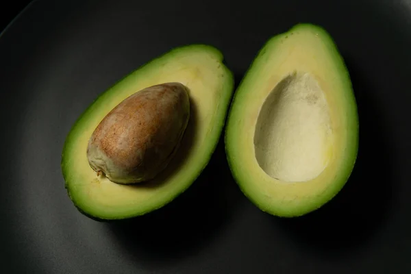 Frische, rohe Avocado in Scheiben auf einem schwarzen Teller — Stockfoto