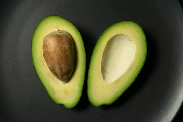 Frische, rohe Avocado in Scheiben auf einem schwarzen Teller — Stockfoto