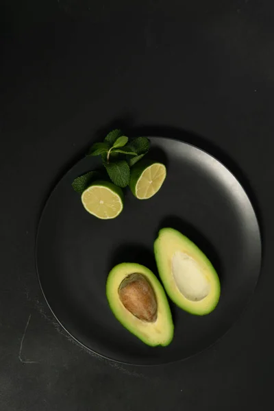 Avocado mit Limetten auf dunklem Hintergrund — Stockfoto