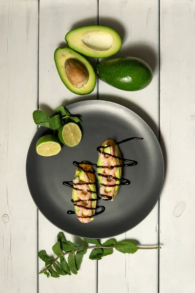 Beyaz ahşap arka planda karides, avokado ve limonlu bruschetta.