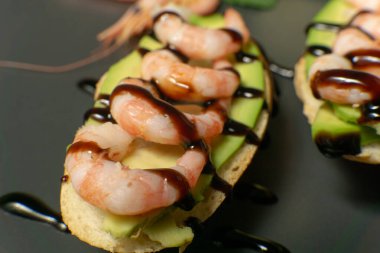 Bir tabakta karides, avokado ve limonlu bruschetta.