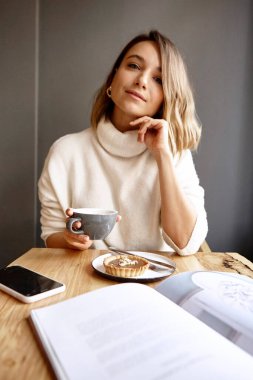 Kadın restoranda masada otururken sıcak çay içiyor.