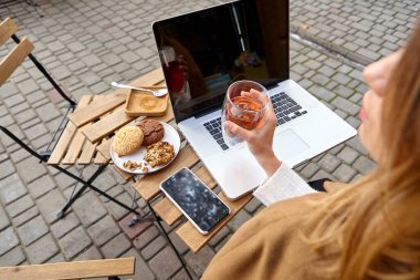 Tatlı tatlı, bir fincan kahve ve masada dizüstü bilgisayarı olan bir kadın eli.