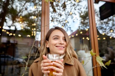 Kadınlar sonbaharda sokakta sıcak çay içer.