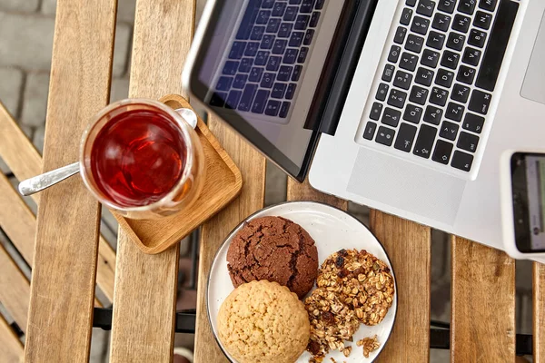 sweet dessert with a cup of coffee and female hands with a phone and laptop at the table