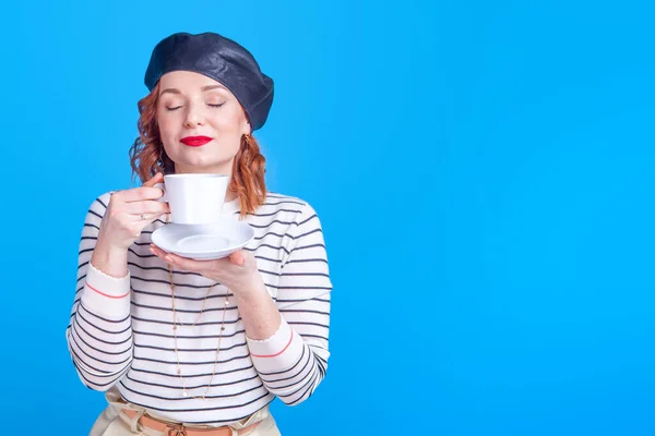 woman with a cup of coffee or tea in the studio on a blue background
