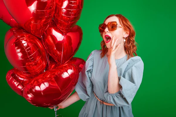 woman with balloons in the form of a heart on a green background in the studio
