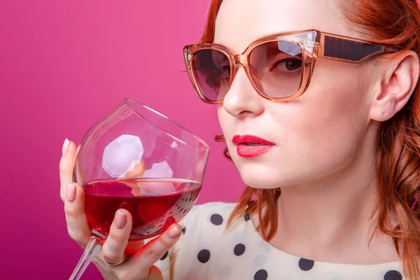 woman with a glass of wine on a pink background in the studio