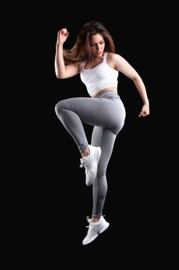 Stüdyoda siyah arka planda poz veren kadın sporcu.