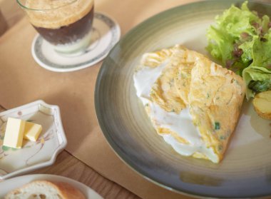 Omlet beyaz yoğurt peynir, patates ve seramik tabak ve gevrek Fransız dilim ekmek, tereyağı, sabahları kahvaltı için ahşap masa kahve organik salata ile