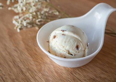Ev yapımı Rum Raisin dondurma ahşap arka plan üzerinde küçük beyaz Kupası kepçe