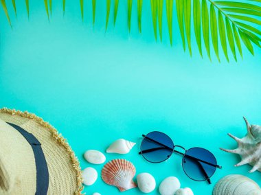 Düz Lay plaj aksesuarları, plaj şapka, güneş gözlüğü plaj deniz ve plaj çakıl üzerinde mavi arka plan ile metin için boş alan ile. Üstten görünüm tatil yaz konsepti.