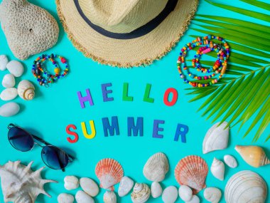 Düz Lay plaj aksesuarları, plaj şapka, renkli tohum boncuk kolye, güneş gözlüğü Merhaba yaz renkli metin, plaj deniz kabuklarını, mercan, plaj çakıl ve Hindistan cevizi hurma yaprağı mavi arka plan ile. Üstten görünüm tatil yaz konsepti.