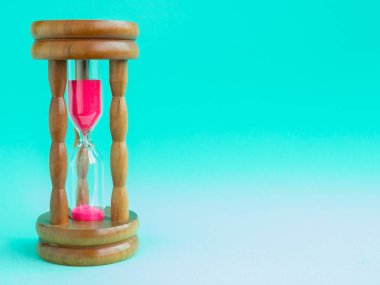 Pembe kum üzerinde mavi arka plan, geri sayım son tarih için geçen sürede ölçmek için ampuller ile çalışan kum ile ahşap Vintage kum saati.