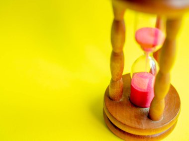 Yakın çekim ahşap Vintage kum saati sarı zemin üzerine pembe kum kum için geri sayım için son tarih geçen sürede ölçmek için ampuller ile çalışan.