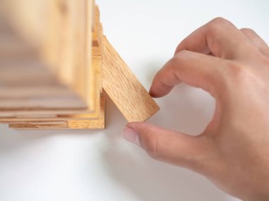 El Beyaz arka plan üzerinde blok oynarken takla Tower ahşap blok oyunu taşıyın. İş kavramı