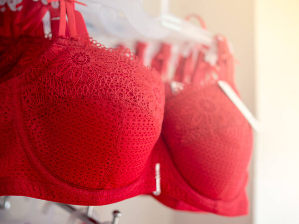 Ряд красных сексуальных кружева бюстгальтеры висит на полке в магазине нижнего белья
