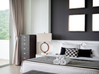 The Gray Wall Interior 'da Dört Kare Paslanmaz Çelik Çerçeveli Modern Yatak Odası Yan Lambalı Yastıklar ve Havlular ve The Glass Sliding Door' un yanındaki ahşap Vintage Dolap.