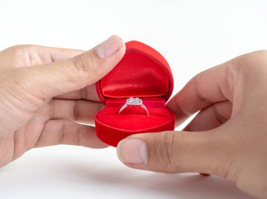 Elmas yüzük elinde beyaz arka plan üzerinde izole kırmızı kalp şekli kutusunda.