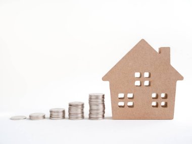 Ahşap ev kopya alanı ile beyaz arka plan üzerinde izole para sikke yığını. Emlak Yatırım finansal kavramı.