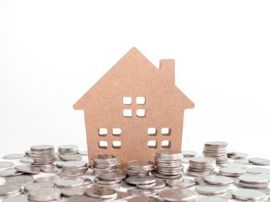 Ahşap ev beyaz arka plan üzerinde izole para sikke yığını. Emlak Yatırım finansal kavramı.