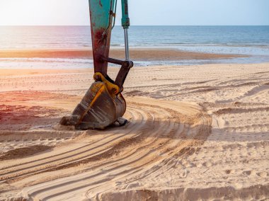 El lastik parça deniz manzarası arka plan üzerinde gelen kum yumuşatmak için sahilde çalışma Ekskavatör.