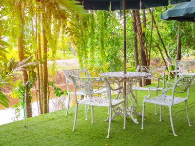 Beyaz vintage çelik tablo yerel ülke içinde belgili tanımlık bahçe katında suni çim üzerinde uzun boylu şemsiye ile ayarla.