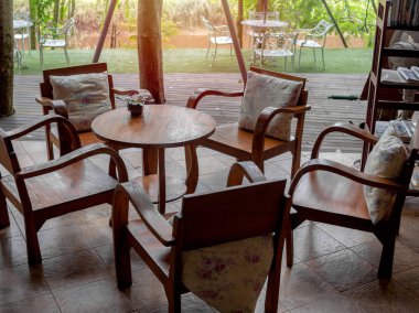 Ahşap koltuklar ile yastık, yuvarlak masa pot ve ahşap kitaplık Cafe ahşap tahta zemin üzerine çiçek ile ahşap masa.