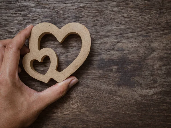 Hand with wooden twin hearts on old wooden texture background with copy space. Love concept.