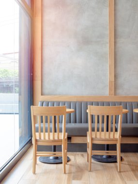 Boş yer beton duvar ve ahşap sandalyeler, ahşap yuvarlak masa ve cam pencere duvarı yakınındaki kafede yerleşik deri kanepe.