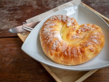 Tatlı üstüne şeker beyaz plaka üzerinde bıçak, çatal o ahşap tepsi ahşap masa arka plan üzerinde ile ekmek.