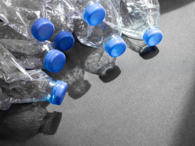 Boş ezilmiş geri dönüşüm plastik içecek su şişeleri üzerinde siyah arka plan ile ışık ve gölge kopya alanı ile temizleyin. Küresel ısınma konsepti.