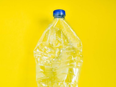 Boş ezilmiş geri dönüşüm plastik içecek su şişesi sarı zemin üzerine temizleyin. Küresel ısınma ve en az kavramı.