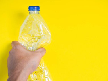 El sıkma geri dönüşüm plastik içecek su şişesi üzerinde sarı arka plan kopya alanı ile temizleyin. Küresel ısınma ve en az kavramı.