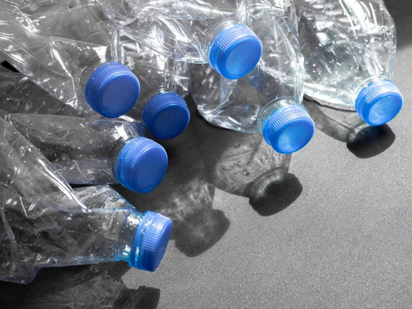 Boş ezilmiş geri dönüşüm plastik içecek su şişeleri üzerinde siyah arka plan ile ışık ve gölge kopya alanı ile temizleyin. Küresel ısınma konsepti.
